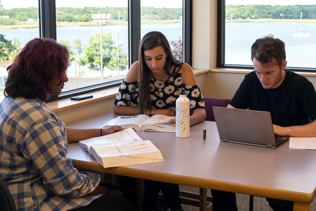 三名东北大学的学生在一张靠窗的桌子上一起学习，可以看到大海