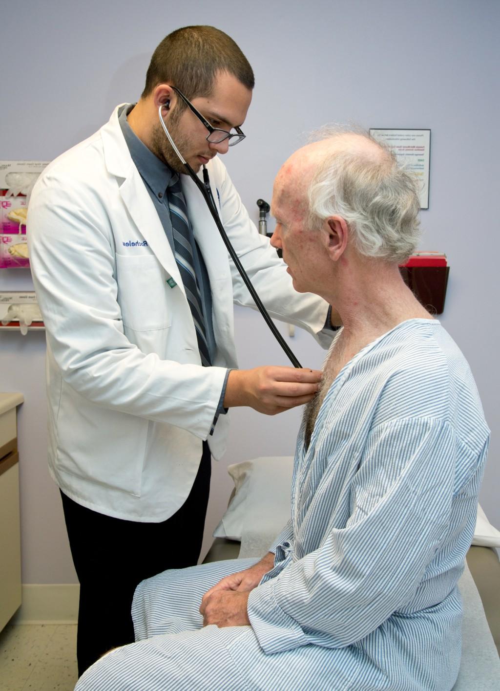 一位医学中心的学生用听诊器听一位老年病人的心跳和呼吸