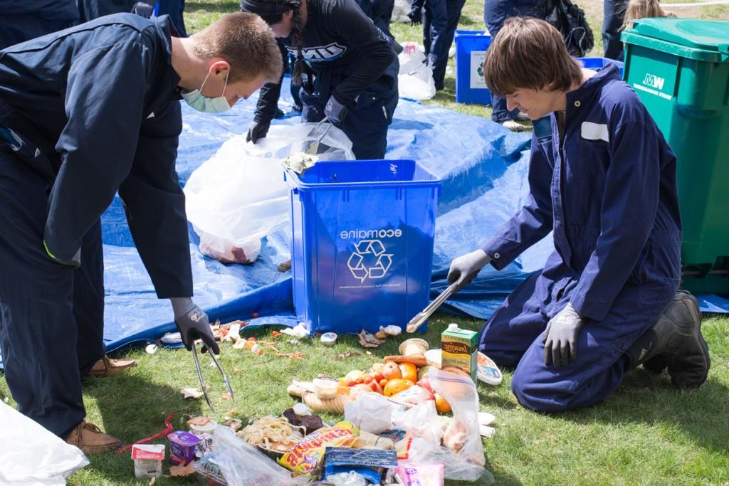 两个穿工作服的学生正在垃圾中筛选回收物品