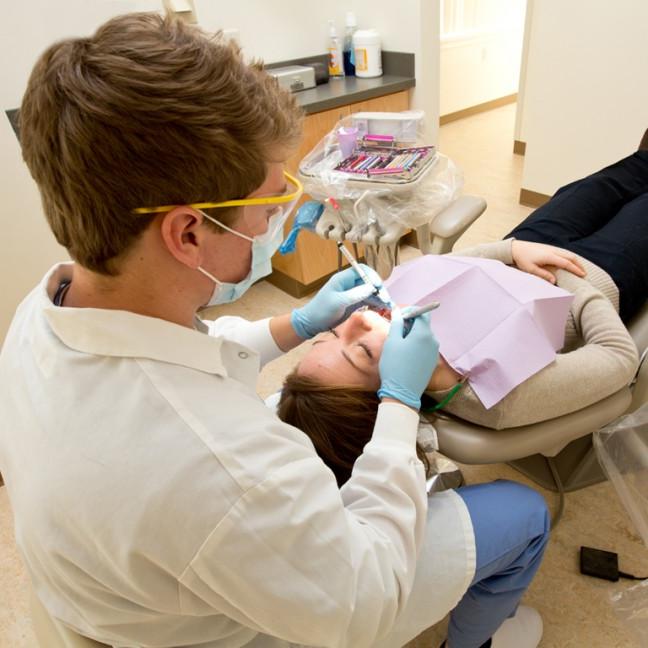 a student performs cleans a patient's teeth